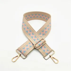 Detail of jacquard woven strap with pink and blue geometric patterns and gold hardware