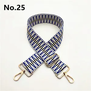 Detail of adjustable woven geometric blue and white bag strap with gold metal hooks