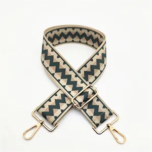Close-up of geometric zigzag patterned woven strap with golden metal swivel hooks