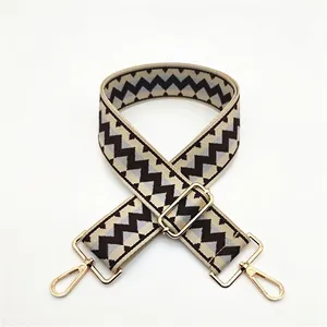 Detail of adjustable woven shoulder strap with geometric zigzag pattern and gold metal hooks