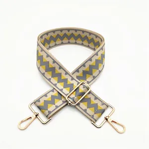 Close-up of geometric woven strap with yellow pattern and golden metal swivel hooks