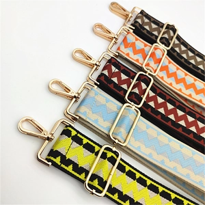 Detail view of colorful geometric woven bag straps with gold metal hooks and adjusters