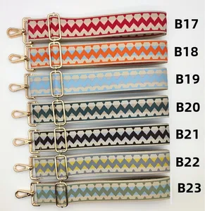 Macro view of adjustable wide woven bag straps with geometric patterns and gold metal clips