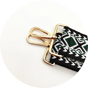 Close-up of geometric embroidered wide bag strap with gold metal lobster clasps