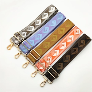 Macro shot of colorful woven bag straps with geometric jacquard patterns and gold metal clips