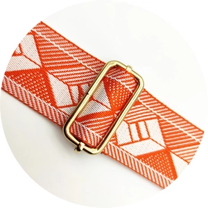Close-up of orange and white diamond weave bag strap with gold metal adjustment buckle