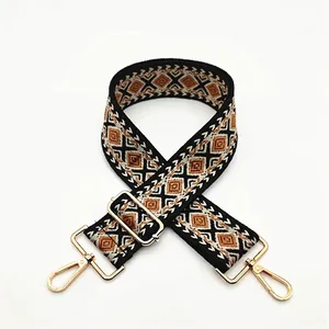 Detail of adjustable geometric patterned bag strap with gold metal lobster clasps