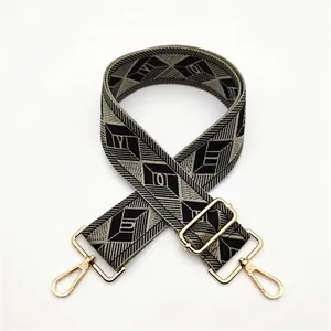 Detail of adjustable wide woven shoulder strap with geometric diamond pattern and gold clips