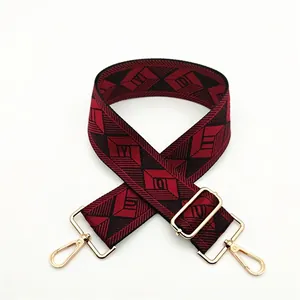 Detail view of red and black geometric jacquard bag strap with gold metal hooks