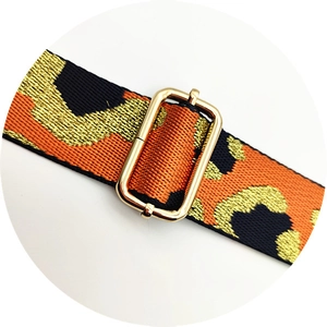 Detail of leopard print bag strap with orange and black pattern and golden buckle