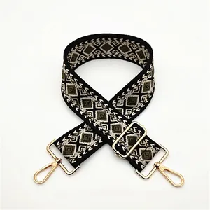 Detail of adjustable woven shoulder strap with geometric diamond pattern and gold metal hooks