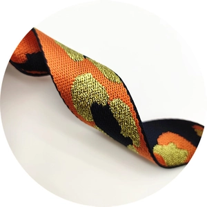 Macro shot of leopard print woven bag strap with orange black and gold metallic threads