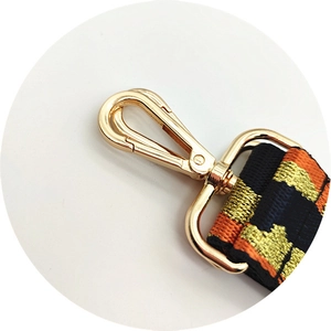 Detail of orange and blue embroidered bag strap with gold lobster clasp closure