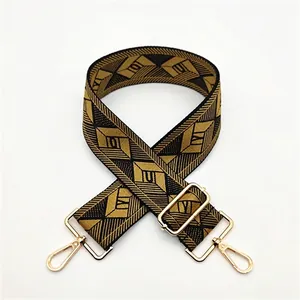Close-up of black and gold geometric woven bag strap with golden lobster clasps