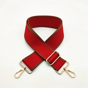 Close-up of adjustable red and brown fabric strap with polished gold metal hooks