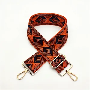 Detail of adjustable geometric wide strap in orange and black with gold metal hooks