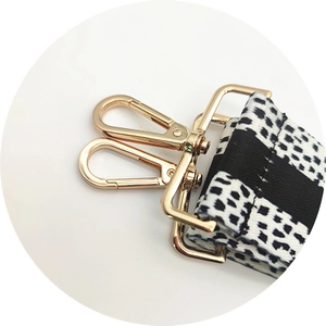 Close-up of detachable pixelated black and white strap with polished gold metal lobster clasps