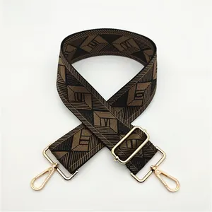 Detail of adjustable geometric patterned bag strap with golden metal hooks and slide buckle
