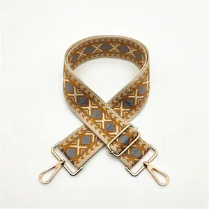 Detail view of ethnic geometric woven strap in gold and grey with metal lobster hooks