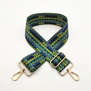 Close-up of geometric pattern bag strap with gold metal lobster clasps and buckles