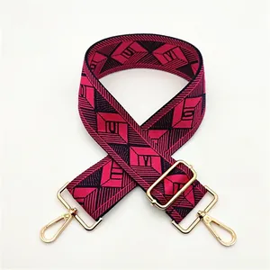 Close-up of a wide red and black geometric woven bag strap with golden metal hardware