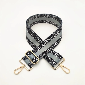 Detail of adjustable black and white woven strap with golden lobster clasps and hardware