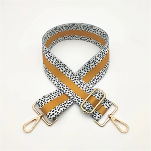 Close-up of mustard yellow and polka dot patterned canvas strap with gold metal hooks