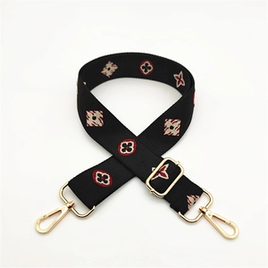 Close-up of a woven bag strap featuring floral patterns and gold metal hooks