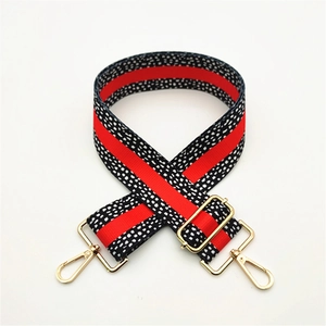 Close-up of adjustable strap with red stripes, black-white dots and golden metal hooks