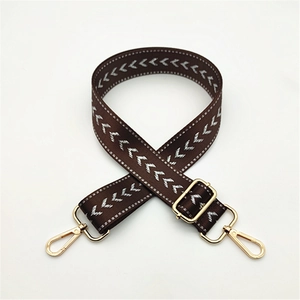 Detail of coffee woven bag strap with white herringbone pattern and gold metal hooks