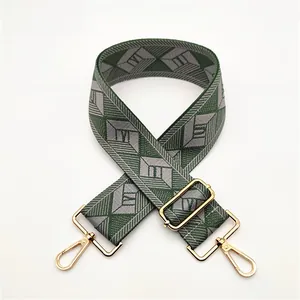 Close-up of green and grey geometric patterned wide shoulder strap with gold metal hooks