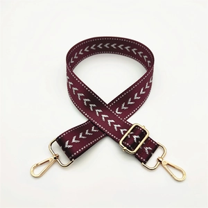 Close-up of wine red woven purse strap with silver arrows and golden hardware