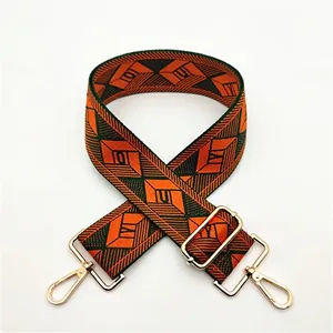 Close-up of geometric jacquard shoulder strap with golden metal clips and adjuster