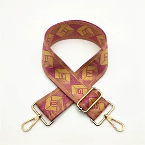 Close-up of jacquard woven wide strap with burgundy gold geometric pattern and metal hooks