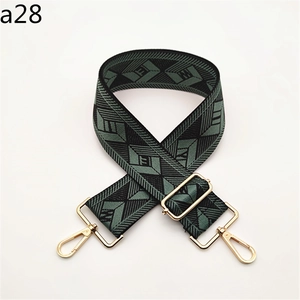 Detail of adjustable woven bag strap in dark green and black with gold hardware