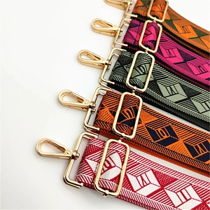 Close-up of colorful woven geometric bag straps with shiny gold metal buckles and clips