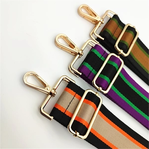 Close-up of adjustable striped handbag straps with polished gold-tone metal hardware hooks