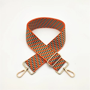 Detail of adjustable woven bag strap with orange and blue geometric pattern and gold buckle