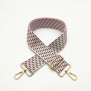 Close-up of pink and black geometric woven bag strap with adjustable gold metal hardware