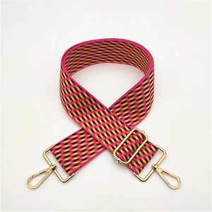 Close-up of woven geometric bag strap in magenta and yellow with gold-tone metal hooks