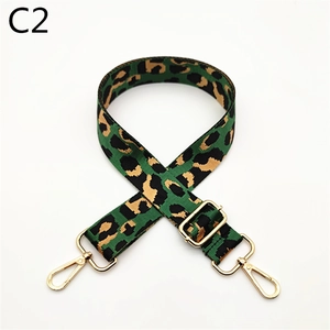 Detail of adjustable leopard print bag strap with green pattern and gold metal hooks