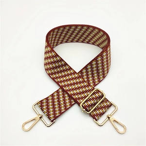 Detail of red and yellow geometric diamond pattern fabric strap with gold metal hooks