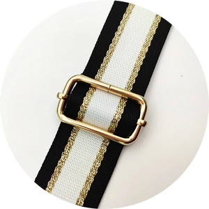 Detail of adjustable black and white striped bag strap with gold metallic thread