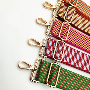 Detail view of woven guitar style bag straps with gold metal hooks and geometric patterns