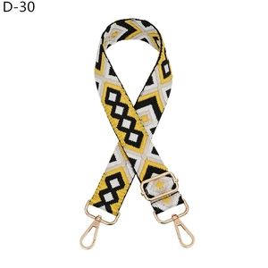 Close-up of geometric yellow and black patterned bag strap with golden metal hooks