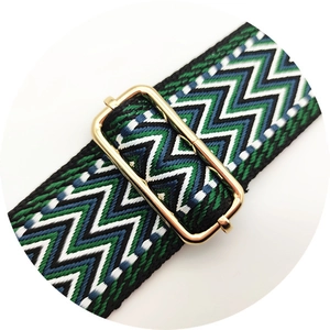 Detail of green and blue woven handbag strap with adjustable gold metal buckle
