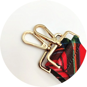 Detail of red tartan bag strap with gold lobster clasps and high-density webbing