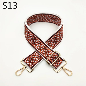 Close-up of adjustable woven bag strap with orange geometric patterns and gold metal buckles