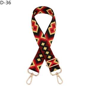 Adjustable geometric bag strap with red, black, and yellow weave and gold metal clasps