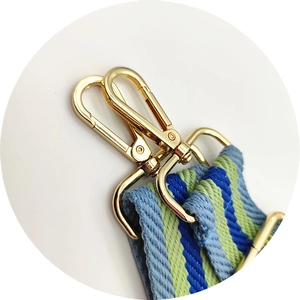 Close-up of woven bag strap featuring blue and green diagonal patterns with gold metal clips